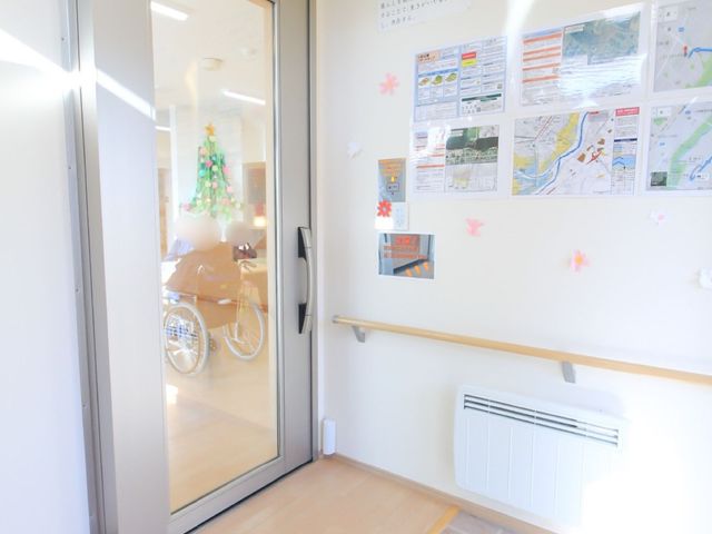 明るいエントランス通路 玄関 エントランスは十分な明るさがあり、壁には情報掲示がされており利用者の方々が日々の活動に役立てられる構造になっています。