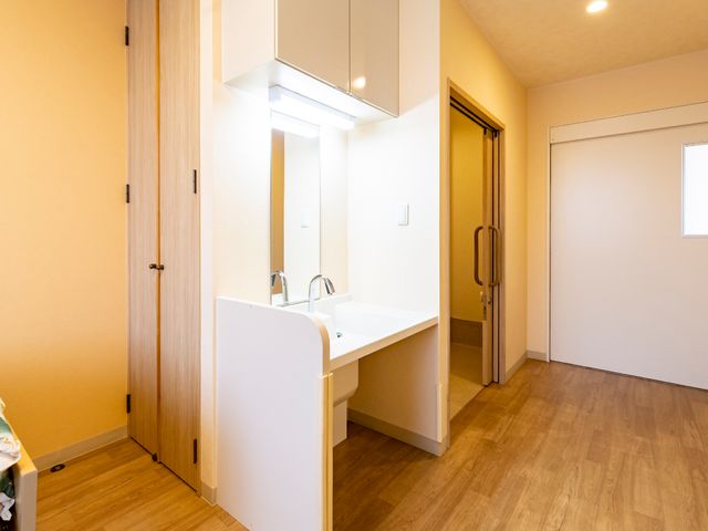 清潔な洗面台の室内 居室 広々とした明るい空間に備え付けられた洗面台は清潔感があります。利用者の日々の快適さを支える設備です。
