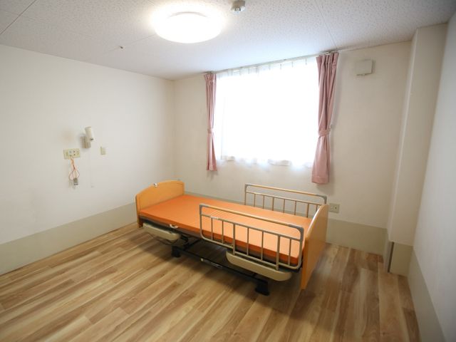 シンプルな居室の様子 居室 落ち着いた色合いのベッドと、自然光の入る清潔な空間です。