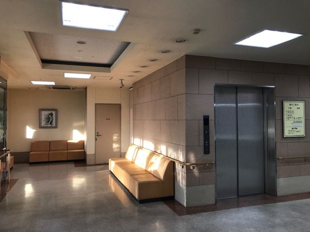 エレベーター前のロビーエリア ゆとりの空間が確保された快適なロビーでは、日差しが心地よい椅子が設置されております。お客様をお迎えする入り口として、暖かく開放的な印象を与えています。