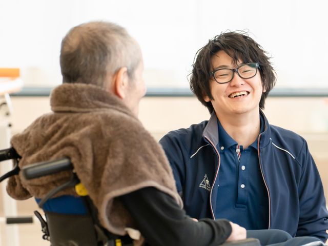 交流中のスタッフと居住者 スタッフイメージ スタッフが寄り添い、利用者と心温まる会話を楽しむ場面です。和やかな環境がうかがえます。