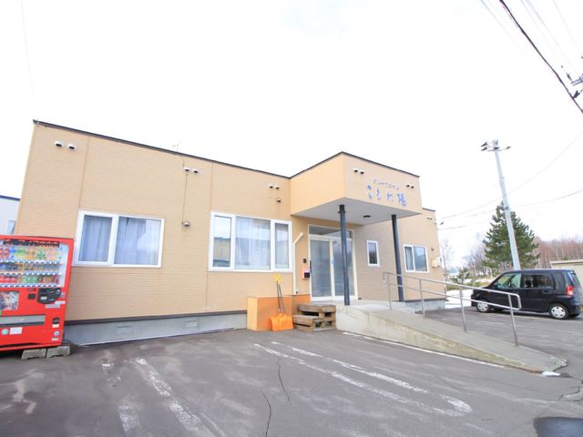 明るい外観の建物エントランス 外観 手すり付きのアプローチでゆったりとした入口が迎える建物です。就業を検討される方にとって、安心の設計が光ります。