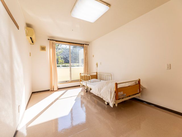 明るい居室の一角 居室 陽当たりの良い部屋で、広々とした空間が確保されています。安全に配慮したベッドが備わっており、快適な居住空間を提供しています。