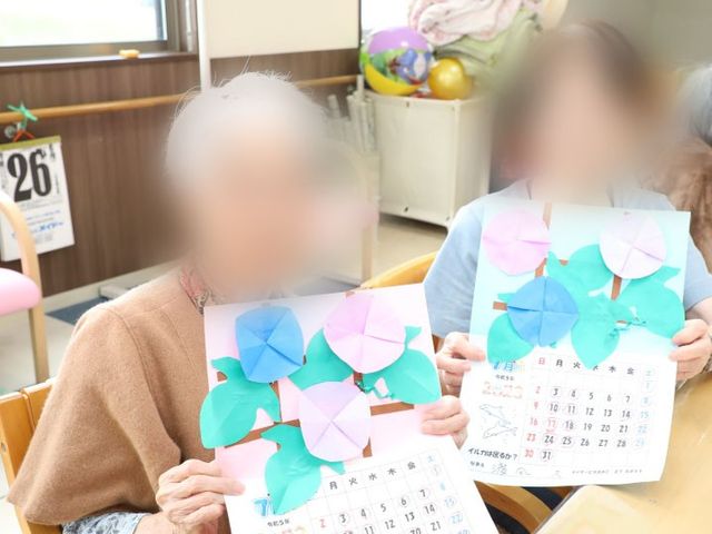 作品展示の場面 多目的室 住人が手作りの作品を楽しそうに見せています。創作活動を通じて交流を深めることができます。