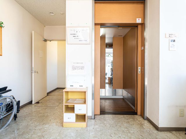 入口付近の廊下 エレベーター ご自宅のような温かみのあるエントランスが、訪れる人を優しく迎え入れます。明るく開放的な空間は、働く環境としても理想的です。