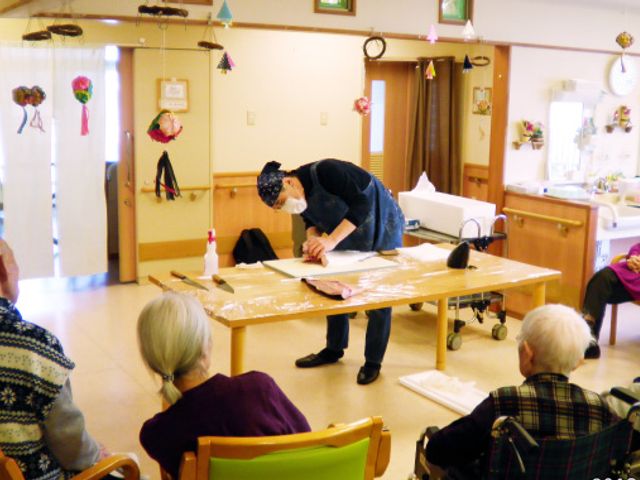 集まる人々と作業台 多目的室 広々とした多目的室で、住民が興味深く作業を見ることができます。交流の場としても活用されています。