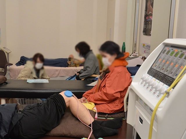 リハビリの様子 機能訓練室 広々とした空間で、リハビリが行われています。利用者とスタッフが一緒に取り組んでいます。