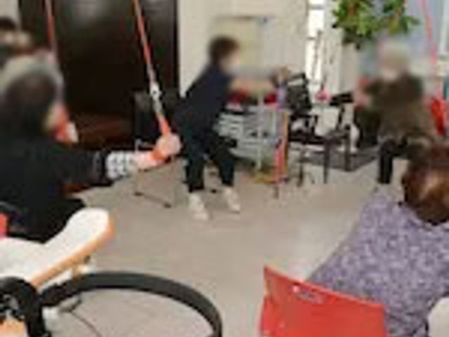 体操する人々の室内 機能訓練室 自然光の中で体操を行う施設です。和やかな雰囲気で運動を楽しめます。