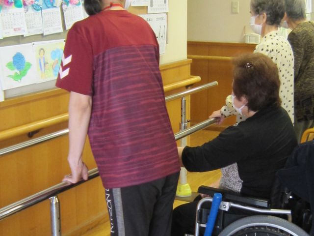 訓練中の様子 機能訓練室 高齢者とスタッフが歩行訓練を行っています。安心してリハビリができる環境です。