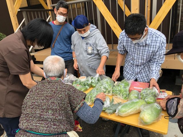 野菜を並べた屋外のテーブル 多目的室 施設の多目的室では、スタッフや利用者が集まる場面が見られます。季節の新鮮な野菜をテーブルに並べ、交流の機会を創出しています。