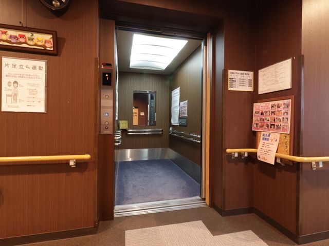 廊下に面したエレベーター入口 エレベーター 敷き詰められたカーペットがアクセントのエレベーター入り口はバリアフリー設計です。周りには掲示物があり、情報が手に取りやすい環境が整っています。