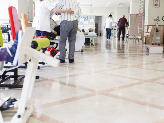 利用者が運動する機能訓練室 機能訓練室 明るく広々とした空間では、利用者の方がリハビリに励んでいます。スタッフがしっかりサポートしています。