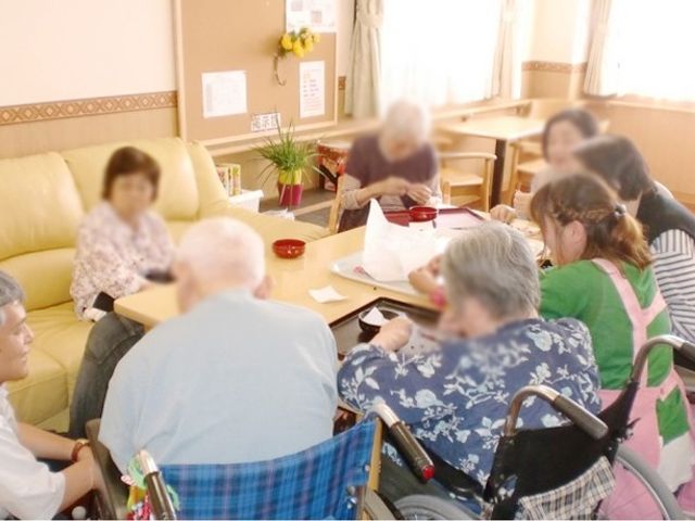 談話中のリビング リビング 広々とした空間で、利用者同士が和やかに交流する様子が見られます。自然光が差し込む明るい場所です。