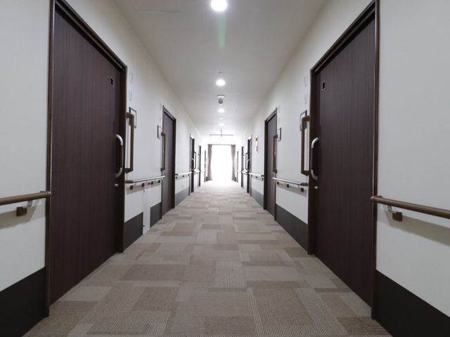 清潔な廊下 廊下 手すりが設置された、ゆったりとした通路は、安心して歩行をサポートします。明るく落ち着いた雰囲気で、居心地の良さを感じられます。