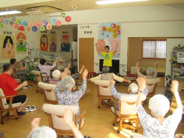 明るいムードの多目的室 多目的室 広々とした明るい部屋で、集まった方々が体操をして健康維持に励んでいます。ゆったりとした時間が流れる居心地の良い空間です。