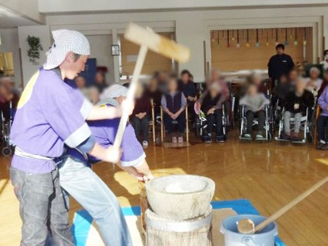 餅つきイベントの様子 多目的室 明るい室内で、餅つきイベントが行われています。幅広い年齢の方が参加して交流しています。