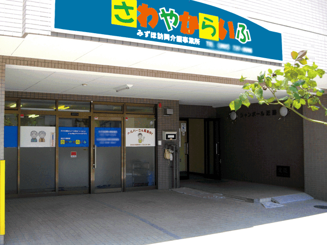 看板のあるエントランス エントランス 施設への入り口はシンプルで使いやすく設計されています。看板が目を引き、安心感を与えます。