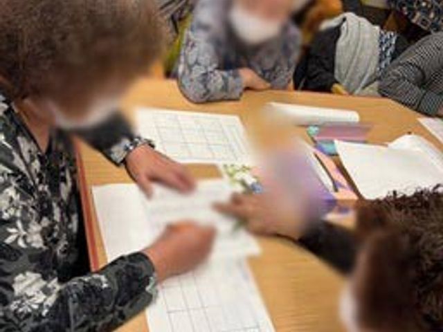 利用者同士が協力する室内 多目的室 広々としたテーブルで利用者同士が楽しく交流しています。温かみのある空間が魅力です。