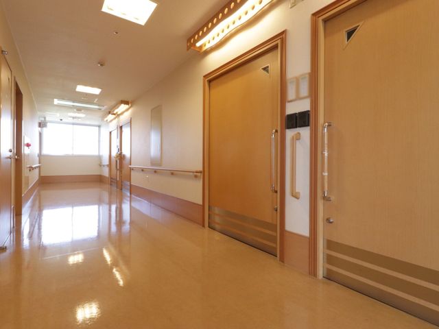 明るく清潔な廊下 通路 床が光を反射して輝く、清潔感のあふれるバリアフリーの廊下です。手すりが設置され、どなたも安心して歩ける設計となっております。
