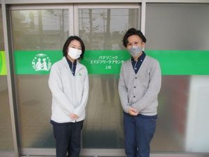 マスク姿の職員2人と玄関  