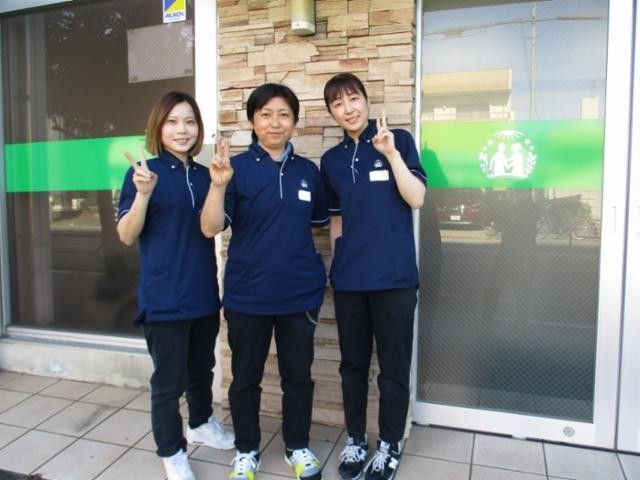 制服のスタッフ三人が並ぶ外観  