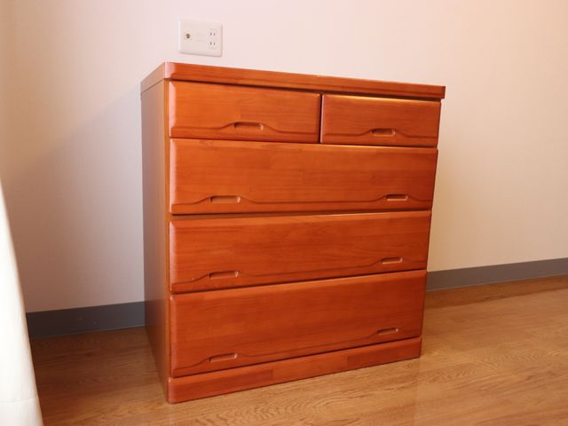木製のチェストが置かれた部屋 家具 洋室に備えられた木製の収納チェストは、利用者の快適な生活空間を支えます。