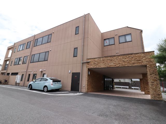 茶色の建物とエントランス 外観 落ち着いた色合いの建物の入口です。モダンなデザインは訪れる方々を暖かく迎え入れます。