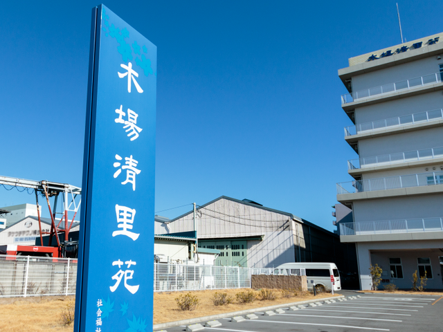 青空の下の外観看板 看板 ゆったりとした日差しの下、青空を背景に佇む施設の看板。安心感を与えるデザインです。