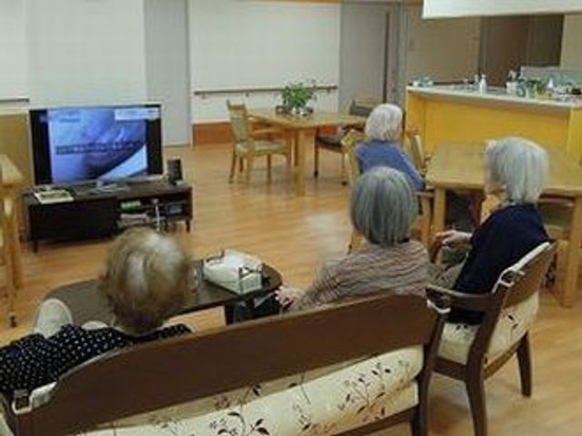 ゆったりとした共有スペース ラウンジ 座り心地の良さそうな椅子に腰掛け、テレビを見る方々の様子が和やかです。安心して日々を過ごせる場所ですね。
