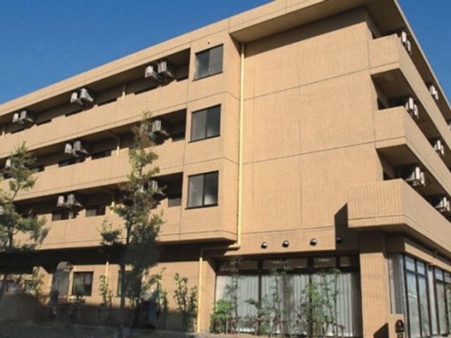 清潔感溢れる建物の正面 外観 清潔で落ち着いた色合いの建物正面です。明るい日差しを反射する窓が印象的で、訪れる方を温かく迎え入れます。
