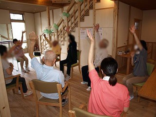 体操中の室内 機能訓練室 明るい空間で体操を行い、利用者同士の交流が活発です。広々とした室内です。