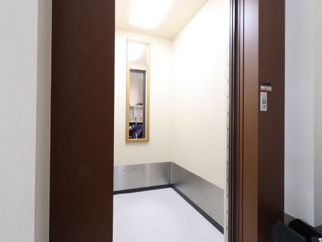廊下の角と反射する鏡 エレベーター 清潔感のある空間で、安心して業務に取り組めます。デザインも機能性も兼ね備えた環境です。