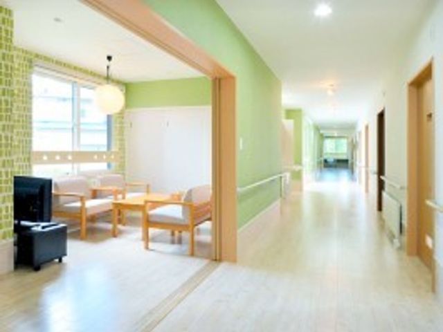 明るく清潔な廊下 リビング 柔らかな光が差し込む廊下は、ゆったりとした椅子が配置され、休憩にも適しています。清掃が行き届き、清潔感が感じられる空間です。