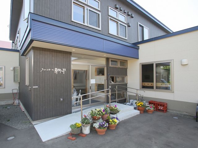 快適なエントランスの外観 玄関 歓迎感溢れる入り口には、明るい色彩の花々が並び、来訪者を温かく迎えています。階段には手すりも設置され、安全に配慮された設計です。