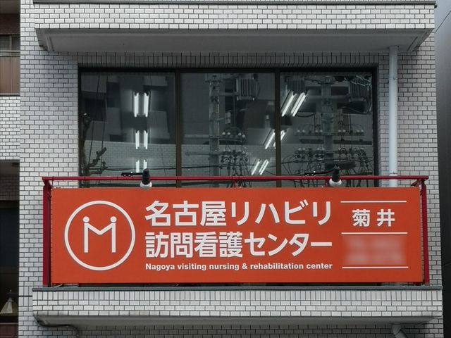 白壁の建物と赤い看板 都市型の建物に目を引く赤く大きな看板があり、明瞭な情報表示で訪れる方々を迎えています。