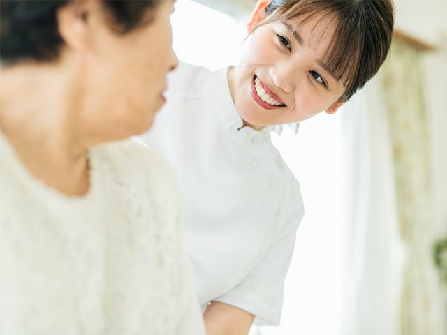 笑顔のケアワーカーと利用者 ケアワーカーが優しい笑顔で利用者に寄り添っており、明るく穏やかな雰囲気が伝わります。職員の温かな対応が、心地よい環境作りに貢献しています。