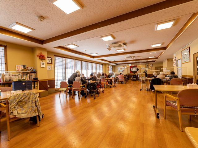 ゆったり食堂の様子 共有スペース 広々とした食堂では、入居者が食事やコミュニケーションを楽しむ様子が見受けられます。木目調のあたたかな雰囲気が広がる場所で、ひとときの安らぎを提供しています。