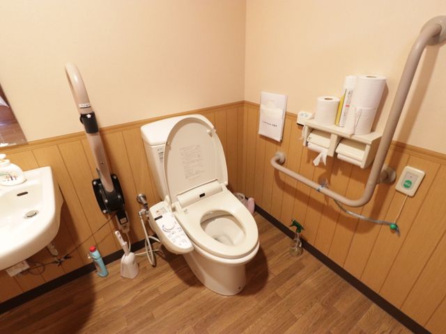 バリアフリートイレ設備 トイレ 手すりや温水洗浄便座が装備された清潔なトイレです。利用者の方々の快適さを追求した配慮が見られます。
