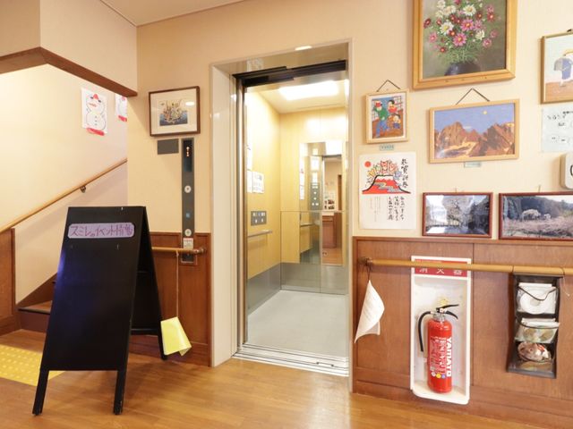 エレベーター前の通路 エレベーター 廊下には色鮮やかな絵が飾られ、心安らぐ空間が広がっています。訪れる方々への温かいメッセージも見受けられます。