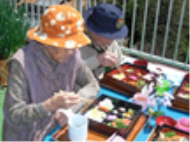 屋外で食事する高齢者 外食 屋外の明るい日差しの下、色とりどりの食事を楽しむ方々の和やかな様子です。自然の中での食事は心身のリフレッシュにもつながります。