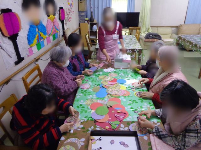 工作中の共有室 多目的室   テーブルを囲んで工作を楽しむ様子が見られる多目的室です。手を動かしながら交流しやすく、和やかな雰囲気が伝わります。