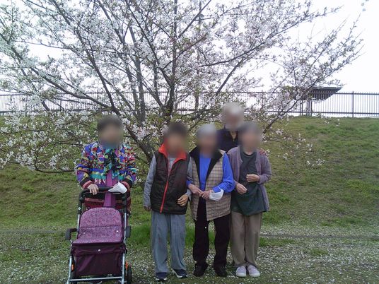 花の木の前に並ぶ利用者たち  