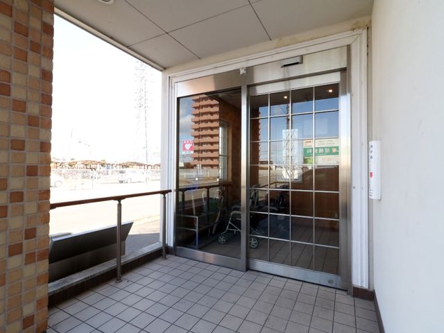 エントランスの自動ドア 出入口 ゆったりとしたエントランスは、日当たりが良く明るい雰囲気を漂わせています。来訪者を迎える開放的な造りが特徴です。