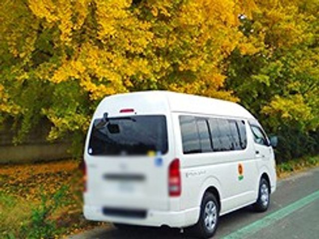 送迎車周辺の風景 外観 黄色く色づいた木々の下にある送迎車が、快適な移動をサポートします。