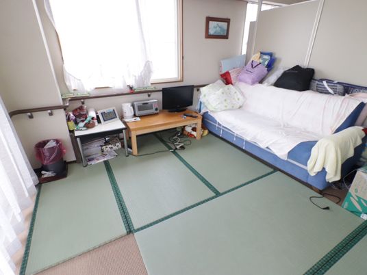 居室は畳である。テーブルの上には小さめのテレビが置かれている。ソファーの状態にされたソファーベッドがある。