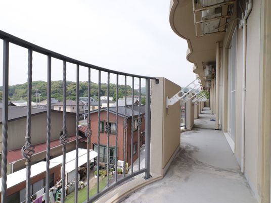ベランダからは周りの景色が見える。他の部屋のベランダと繋がっている。転倒防止の柵が取り付けられている。