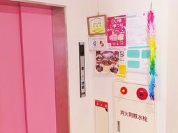 ピンクのエレベーター扉と掲示物
