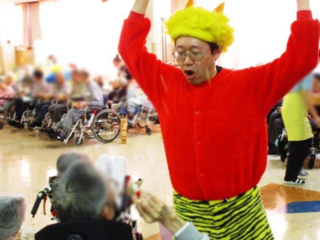 楽しげな催しの様子 多目的室 明るい部屋で楽しく踊る様子です。多くの利用者が集まり、和やかな雰囲気が漂っています。