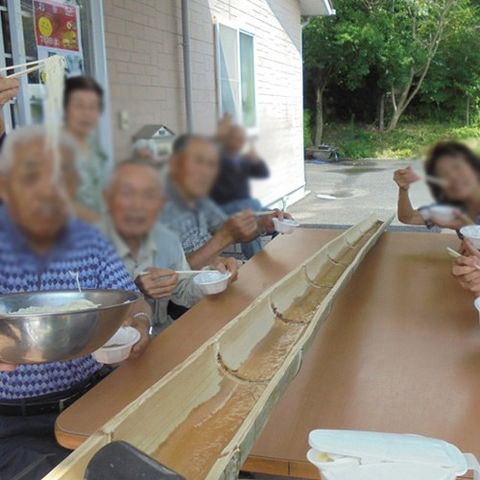 流しそうめんを楽しむ中庭 中庭 自然が感じられる中庭で、入居者の皆さんが流しそうめんを楽しんでいます。和気あいあいとした雰囲気です。