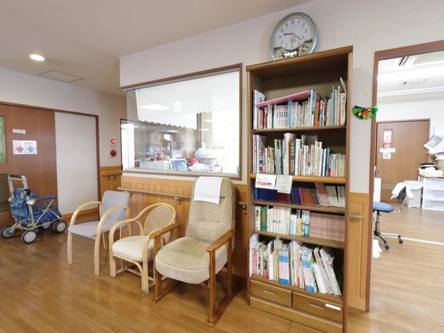 共有スペースの明るい光景 読書スペース ゆったり座れる椅子と本の揃った書棚があり、リラックスできる読書スペースが整っています。暮らしの憩いの場として利用されるラウンジの一角です。